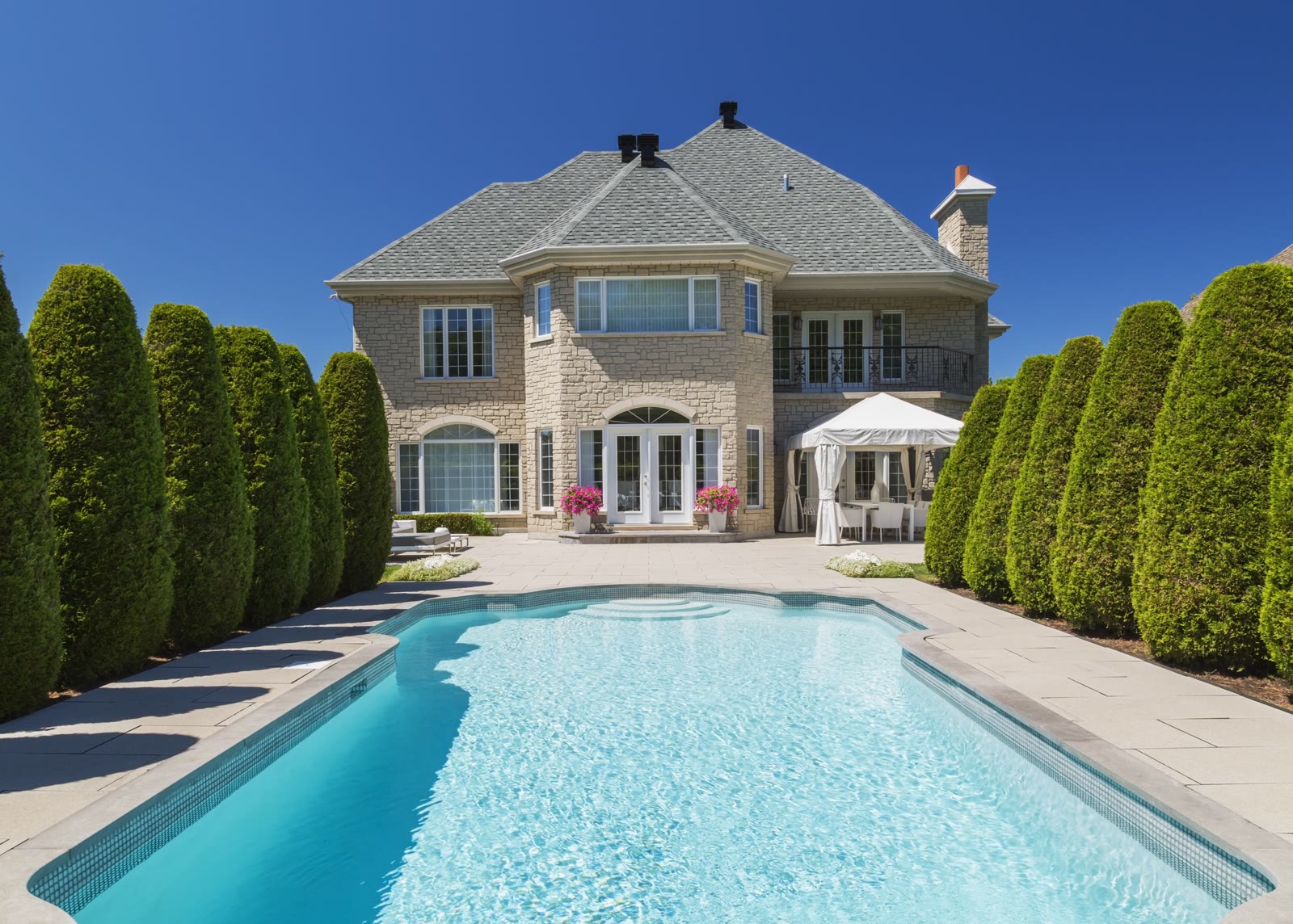 Two-story stone house with a pool and patio being prepped for washing