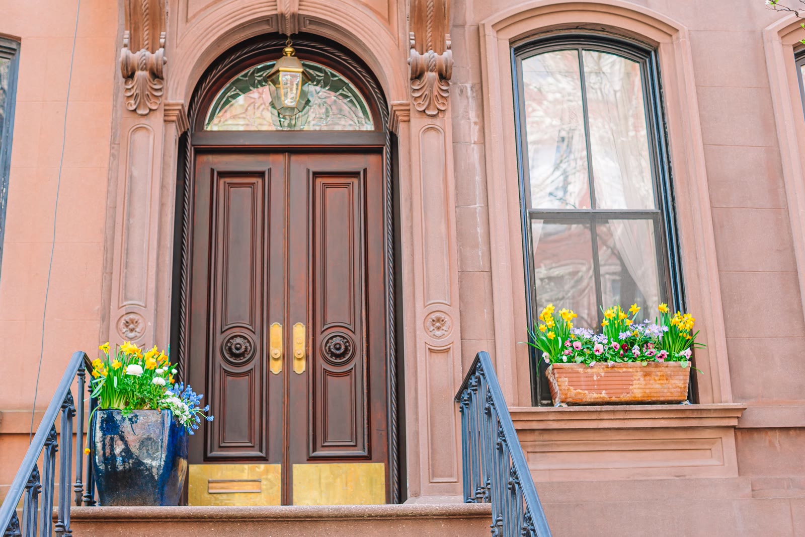 Brownstone entrance with carved double doors and flower boxes