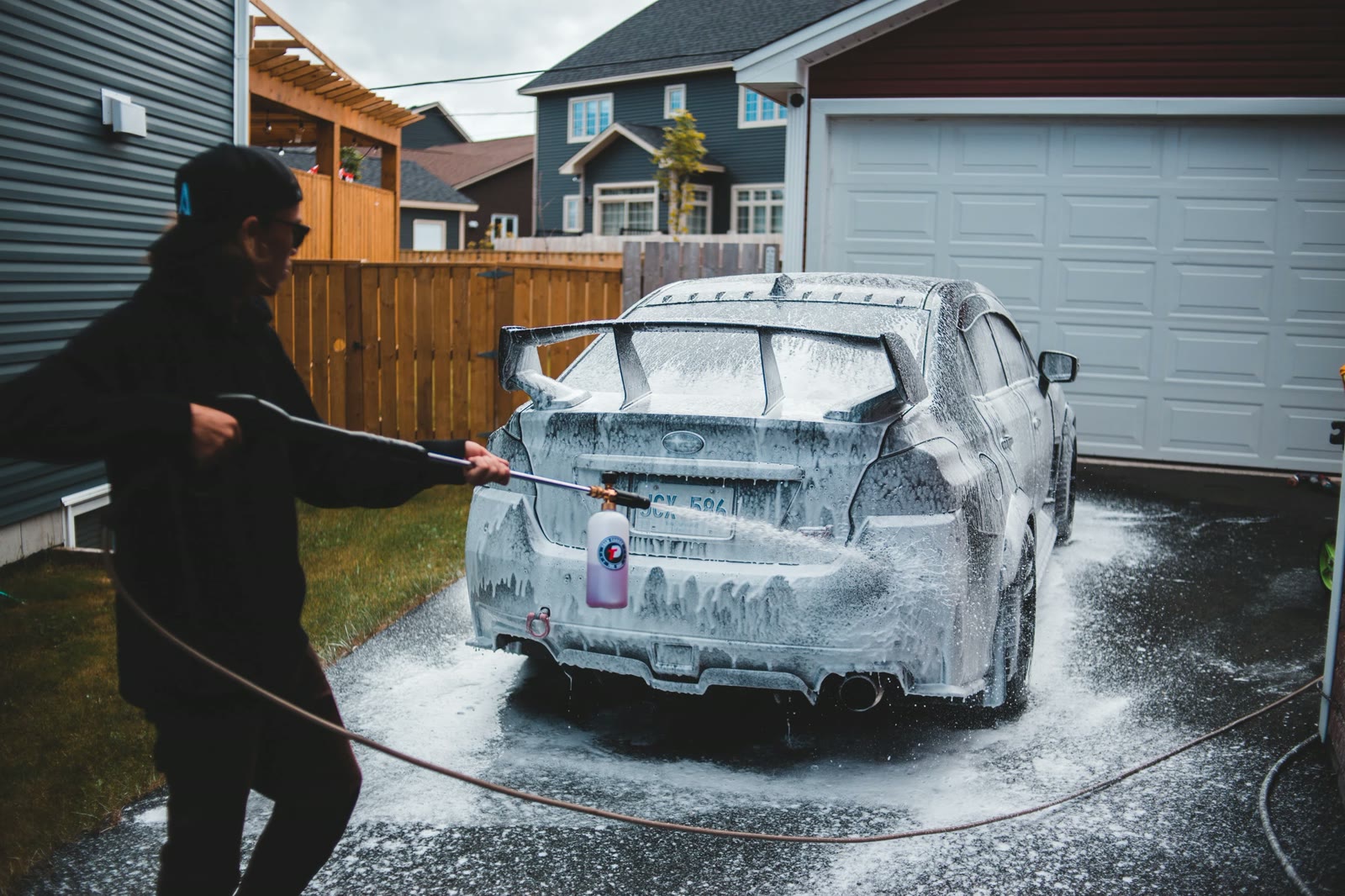 MintWash detailer covering a car in thick foam with a pressure washer at a curbside