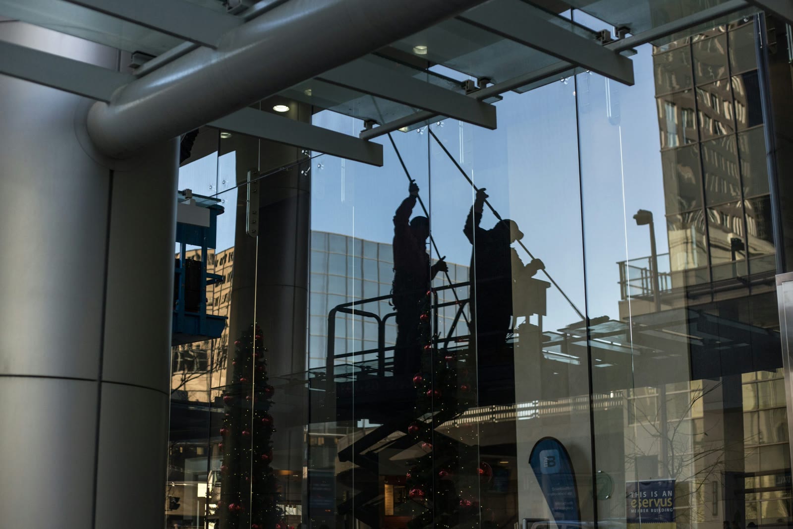 Reflections of window washers on the glass facade of a city building
